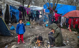 Eine Migrantenfamilie versucht, sich an einem kleinen Feuer in einem provisorischen Lager neben dem Lager in Moria aus Lesbos zu wärmen. - picture alliance/dpa