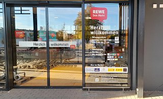 An der Tür zum neuen Rewe wird angezeigt, welche Geschäfte drinnen außerdem zu finden sind, darunter die Post. - Simone Flörke