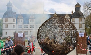 Bei der Aktion von Künstler Arndt Drossel wird eine symbolische Weltkugel aus Draht entflammt, um sie gemeinsam wieder zu löschen. - Moritz Jülich