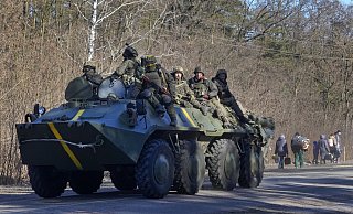 Ukrainische Soldaten auf einem gepanzerten Mannschaftswagen fahren an Menschen vorbei, die ihre Habseligkeiten auf der Flucht vor dem Konflikt tragen, in der Region Wyschgorod in der Nähe von Kiew. - dpa