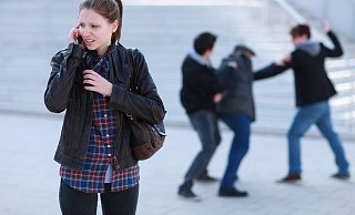 Eine junge Frau ruft Hilfe, während im Hintergrund eine Auseinandersetzung stattfindet. - Polizeiliche Kriminalprävention der Länder und des Bundes
