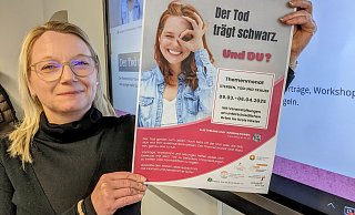 Netzwerkkoordinatorin Meike Gast präsentiert das Plakat zum Themenmonat Tod. - Burkhard Battran