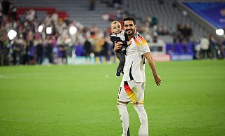 DFB-Kapitän Ilkay Gündogan geht nach dem Spiel gegen Schottland mit seinem Sohn auf dem Arm über den Platz. - Christian Charisius/dpa