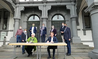 Unterschriften in Zeiten der Pandemie: Vor den Türen des Historischen Rathauses unterzeichneten die Spitzen von CDU und Grünen um Sigrid Beer und Daniel Sieveke (am Tisch) den Koalitionsvertrag. Im Hintergrund Markus Rieger und Klaus Schröder (Grüne), Bürgermeister Michael Dreier, Petra Eichstadt und Christian Müller-Albers (CDU). - Benedikt Riemer