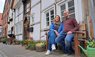 Ulrike und Markus Mell sitzen vor ihrem Fachwerkhaus am Großen Wall. Dessen Front haben sie herbstlich dektoriert, auch wenn sie dort Ende August ausgezogen sind. - Marion Pokorra