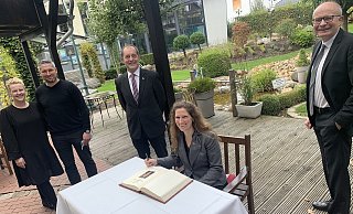 Ins Goldene Buch der Gemeinde Hövelhof trug sich US-Generalkonsuli Fiona Evans auf der Terrasse des Hotel Victoria ein. Interessierte Zuschauer waren (v. l.) die Gastgeber Victoria Förster-Streblau und Nico Streblau, Hövelhofs stellvertretender Bürgermeister Michael Kersting und der CDU-Landtagsabgeordnete Bernhard Hoppe-Biermeyer. - Jens Reddeker