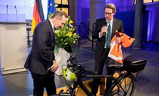 Volker Wissing (FDP, l), Bundesminister für Verkehr und Digitales, nimmt von Andreas Scheuer (CSU), scheidender Bundesminister für Verkehr und digitale Infrastruktur, bei der Amtsübergabe im Bundesministerium für Verkehr und Digitales einen Fahrradhelm und weitere Ausrüstung entgegen. - Foto: Christoph Soeder/dpa