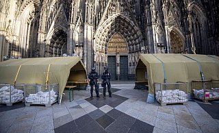 Polizisten mit Maschinenpistolen stehen vor dem Kölner Dom. Nach dem Terroralarm für das Gotteshaus sind drei weitere Verdächtige festgesetzt worden. - Thomas Banneyer/dpa