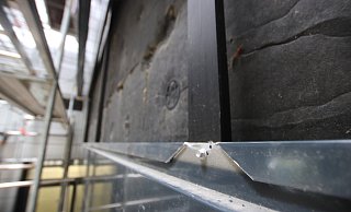 Kaputt: Die Rathausfassade wird derzeit von Arbeitern neu verschraubt. - Ulf Hanke