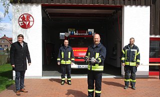 Bürgermeister Nicolas Aisch (v. l.), Frank Peine, Chef der Löschgruppe in Großeneder, Drohnenpilot Martin Koke und Stadtbrandinspektor Sebastian Göke stellen am Feuerwehrgerätehaus in Großeneder die neue Drohne vor. - Löschgruppe Großeneder