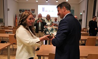 Kreisdirektorin Manuela Kupsch gratuliert dem alten und neuen Landrat mit einem süßen Präsentkorb - seine Frau Kristina bekam Blumen. - Neue Westfälische