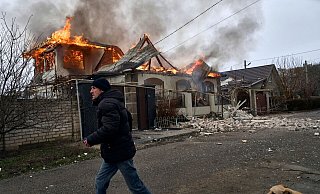 Ein Anwohner läuft an einem brennenden Haus in Cherson vorbei, das nach ukrainischen Angaben bei russischem Beschuss am orthodoxen Weihnachtsabend getroffen wurde. - Libkos/AP/dpa