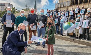 Pit Clausen (v.l.) nimmt den offenen Brief der Initiative Bielefeld handelt! von Nina Knust entgegen.  - Sarah Jonek