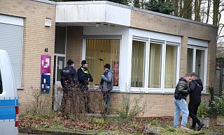 Während der Razzia: Uniformierte Polizisten und zivile Kräfte stehen vor dem Gebäude am Ortsrand von Hiddenhausen. - Moritz Trinsch
