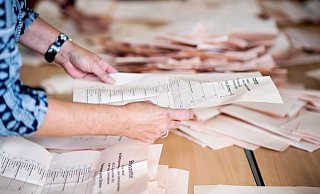 Eine Wahlhelferin sortiert in einer Grundschule die Stimmzettel für die Auszählung. - Foto: Hauke-Christian Dittrich/dpa