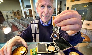 In einer Hand hält der Gütersloher Detlef Jentsch den Orden Isabellas der Katholischen, in der linken eine bronzene Gedenkmedaille zur Weihe des Berliner Doms, die Kaiser Wilhelm II. und Gemahlin Auguste Victoria zeigen. - Andreas Frücht