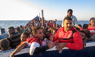Ein überladenes Holzboot mit Flüchtlingen treibt im Juli nahe der libyschen Küste. Die sichtbaren Rohre dienen der Belüftung der Zwischenkammern, in denen sich ebenfalls Flüchtlinge befinden. - Bastian Schlange