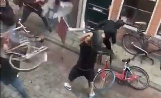 Das Video zeigt unter anderem, wie ein Mann (r.) einen Stuhl in die Gruppe der Bielefelder Fans schleudern will. Diese wehren sich, indem sie Fahrräder und Tische in seine Richtung schleudern. - Screenshot: Twitter / sandervh1998