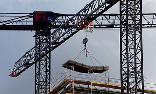An einem Baukran wird Baumaterial auf einer Baustelle des Quartiers Heidestraße in Berlin transportiert. - Carsten Koall/dpa