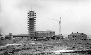 Auf freier Fläche: Eine Kirche im Stil der 1960er Jahre mit viel rotem Klinker wird hier errichtet. Der Turm ist noch eingerüstet, darüber schaut der Wetterhahn hervor. - Georg Heese (Kommunalarchiv)
