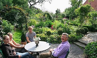 Von der Terrasse aus und der Sitzecke davor bietet sich ein herrlicher Blick ins Grüne - vorn der Bauerngarten, dem sich die Obstwiese anschließt. Der Hohlweg (l.) verbindet die Flächen. Auf dem Foto v.l. Irina Hanke mit Mutter Brigitte, Sohn Florian und Friedhelm Diebrok vom NABU. - FOTO: DIETER SCHNASE