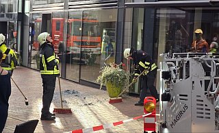 Die Einsatzkräfte der Gütersloher Berufsfeuerwehr kehren die Glassplitter der herabgestürzten Fassadenscheibe zusammen. - Kevin Hermann