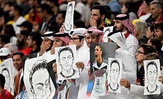 Zuschauer halten Bilder von Deutschlands ehemaligem Nationalspieler Mesut Özil in die Höhe. - Federico Gambarini/dpa