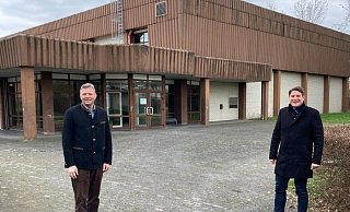 Matthias Goeken (l.) und Nicolas Aisch stehen vor der zurückzubauenden Zweifach-Sporthalle mit Baujahr 1980 im Schulzentrum Borgentreich, die durch eine neue Multifunktionshalle ersetzt werden soll. - Orgelstadt Borgentreich