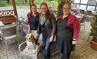 Stefanie Launert (v.l), Tatjana Böselt und Bianca Stratmann freuen sich, endlich wieder Gäste im Alt Hiddenhausen begrüßen zu dürfen. Unterstützt werden sie von Beagle Nils. - Benedikt Riemer