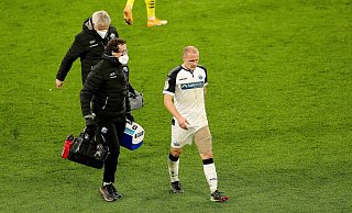 Sven Michel muss im Pokalspiel beim BVB nach gut 20 Minuten mit bandagiertem linken Oberschenkel den Platz verlassen. Begleitet wird er von Physiotherapeut Jörg Liebeck (vorne) und Mannschaftsarzt Hans-Walter Hemmen. - picture alliance