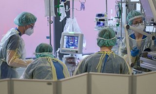 Pflegerinnen und Pfleger sowie eine Ärztin kümmern sich auf der Intensivstation um einen Patienten. - Foto: Sebastian Gollnow/dpa