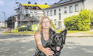 Obdachlos: Nadine Theismann mit ihrer Hündin Loona vor dem ausgebrannten Wohnhaus (hinten) am Hartlager Weg. - Andreas Zobe