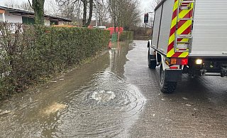Nach dem Hochwasser sprudelt das Wasser aus der Schachtabdeckung des Kanalnetzes auf die Hainanger-Straße in Germete. - FFW Warburg