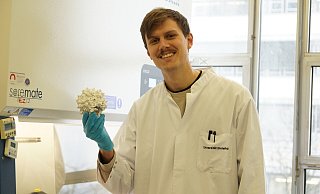 Biotechnologe Marco Radukic von der Universität Bielefeld hält ein Virus-Partikel aus dem 3D-Drucker in der Hand. - Daniela Driftmeier