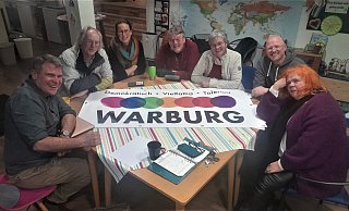 Der Arbeitsgruppe „Buntes Fest“ für Warburg mit Stephan Rumphorst (v. l.), Willi Bott, Mirja Magenheim, Andreas Knoblauch-Flach, Doris Hauck, Stefan Wiegand und Hilla Zavelberg-Simon. In der Mitte des Tisches liegt ein Banner mit dem neuen Logo. - Simone Flörke
