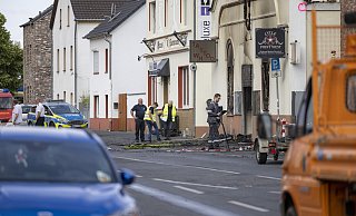 Blick durch das Absperrgitter auf das ausgebrannte Motorradgeschäft in Sankt Augustin. Nach dem Brand mit zwei toten Feuerwehrleuten laufen die Ermittlungen zur Brandursache. - picture alliance/dpa