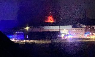 Bei Eintreffen der Feuerwehr schlugen die Flammen aus dem Dach der Halle. Darin wurden zwei Sattelzüge und ein Wohnmobil komplett zerstört. - Aileen Tholen