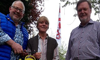 Christian Voigt (v.l.), Burkhard Scheiding und Sabine Detzmeier vom Gartenbauverein. Hinten hängt die Fahne von Südlengern, Christian Voigt hat ein schmiedeeisernes Vereinslogo angefertigt. - Meiko Haselhorst