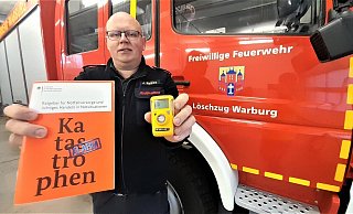 Warburgs Feuerwehrleiter Jürgen Rabbe zeigt die wichtige Bürgerbroschüre, die es kostenfrei gibt, und den mobilen CO-Warnmelder der Feuerwehr. Ein solches Gerät, das ähnlich aussieht wie ein Rauchmelder, gibt es auch für die private Wohnung. - Simone Flörke