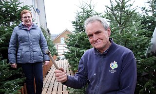 Manfred Schröder und Helferin Melanie Allen im Eingangsbereich des Weihnachtsmarktes. Der Weg durch die Tannen führt auf eine große Fläche, auf der einige Buden stehen - und ein großer Baum. - Archivfoto: Meiko Haselhorst