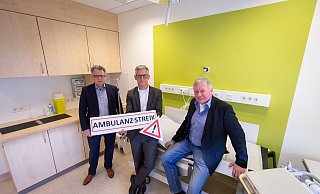 Josef Düllings (v.l.), Siegfried Rörig und Achim Schäfer stehen und sitzen in einem Behandlungszimmer der Ambulanz, die während des Streiks geschlossen bleiben wird. - Niklas Tüns