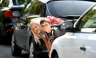 Karlotta und Janne (beide 7) stehen zwischen zwei Autos und checken den Autoverkehr. - Symbolforo: Holger Hollemann/dpa