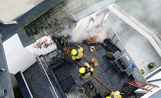 Blick aus dem Korb des Gelenkmastes auf die Brandstelle. Feuerwehrleute bei den Löscharbeiten am Abstellraum. Auf dem Balkon wurde auch Mobiliar durch die Flammen zerstört. - Feuerwehr Bad Lippringe