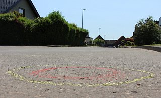 Mehr als 30 gelb-rot markierte Kreise (das Bild zeigt einen davon) auf der Straßendecke in der Salzufler Sackgasse deuten genau auf die Stellen hin, wo die Spurensicherung am Einsatzort Patronenhülsen sichergestellt hat. Fünf Kugeln trafen den immer noch schwer verletzten 19-jährigen Fahrer. - Janet König