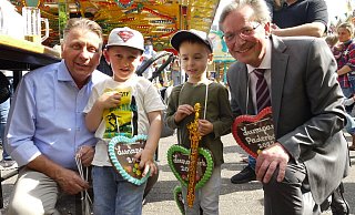 Der Vorsitzende des Paderborner Schaustellervereins Hans-Otto Bröckling (l.) und Bürgermeister Michael Dreier verteilen nach der Eröffnung des Lunaparks Lebkuchen-Herzen an die Kinder. Hier freuen sich Milan (l.) und Elias aus Paderborn. - Lisa Richter