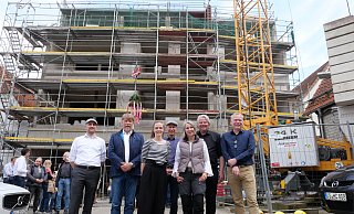 Noch baumelt der Richtkranz am Kran. Darüber, dass der Rohbau steht, freuten sich die Investoren Marc Damstra (r.), Jan-Chris Damstra (2. v. r.) und Andrea Rudkowski (3. v. r.) gemeinsam mit dem Lübbecker Baudezernenten Joachim Schaer (v. l.), Architekt und Bauleiter Andreas Steinmeier, Projektarchitektin Lisa Blotevogel und Bürgermeister Frank Haberbosch beim Richtfest Scharrnstraße 11-13/Steinweg 6. - Kirsten Tirre