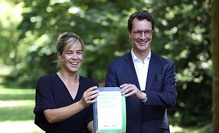 Grünen-Chefin Mona Neubaur und Ministerpräsident Hendrik Wüst (CDU) mit dem Koalitionsvertrag. - picture alliance/dpa