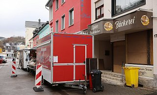 Verkaufswagen stehen rund ein halbes Jahr nach dem Hochwasser in Schleiden-Gemünd vor leeren Geschäften in der Fußgängerzone. Die Stadt in der Eifel wurde bei dem Hochwasser im Juli 2021 schwer getroffen. - picture alliance/dpa
