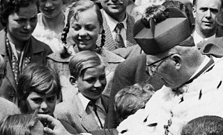 Auf diesem Foto aus der zweiten Hälfte der 1960er Jahre zeigt sich Erzbischof Lorenz Jaeger im Kardinalsrang nach einer Libori-Eröffnungsfeier vor dem Dom Kindern zugewandt. - Sammlung Stüken