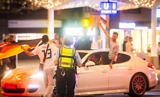 Eine Polizistin weist die deutschen Fans beim Autokorso auf die Gefahren hin. Der Lerneffekt bleibt jedoch aus. - Mike-Dennis Müller / www.mdm.photo